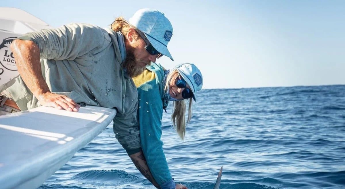 A charter captain and client leaning over the gunwale on open water